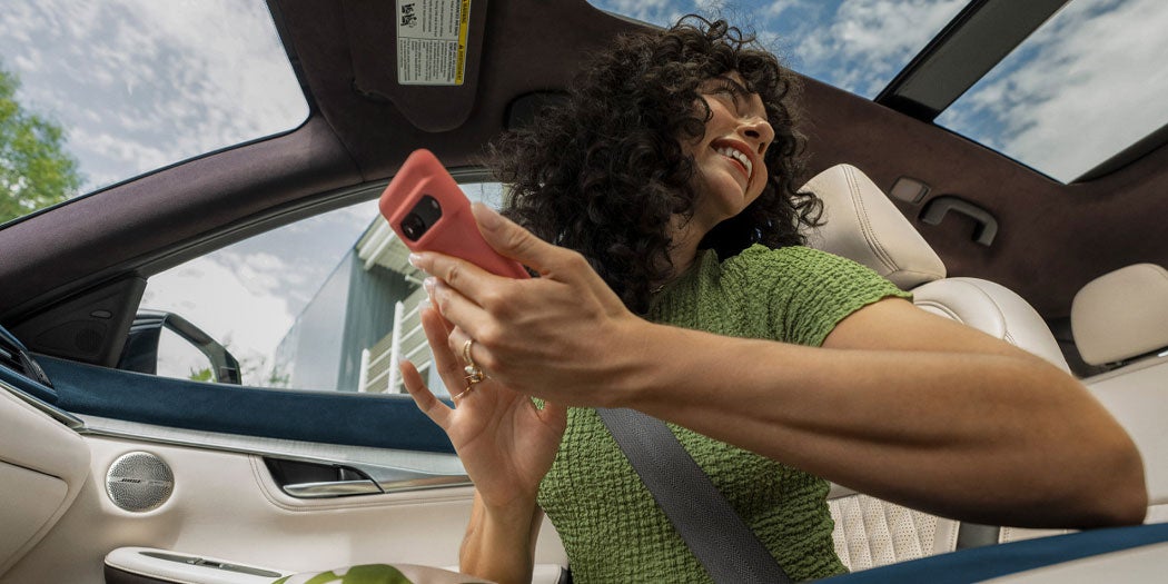 Woman smiling and holding a phone inside a car